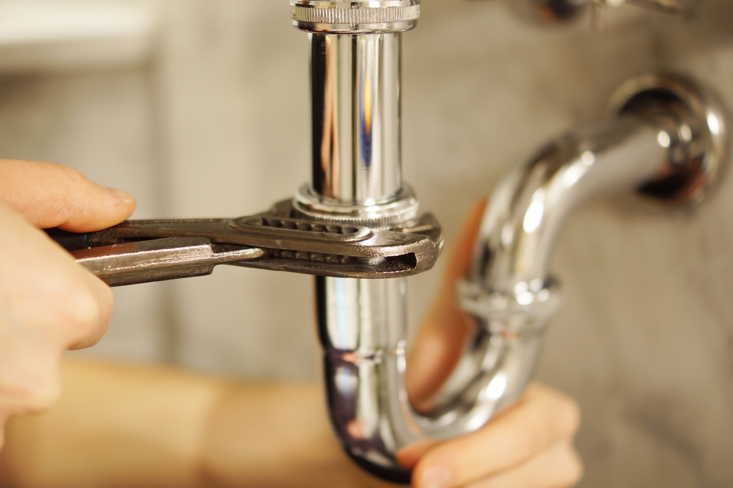 Plumber tightening a chrome pipe